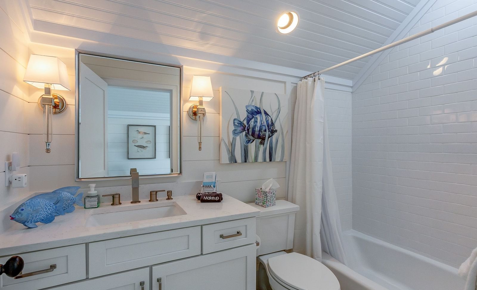 a bathroom with a curtained bathtub, a commode, a mirror and a sink with drawers at Abaco Inn.