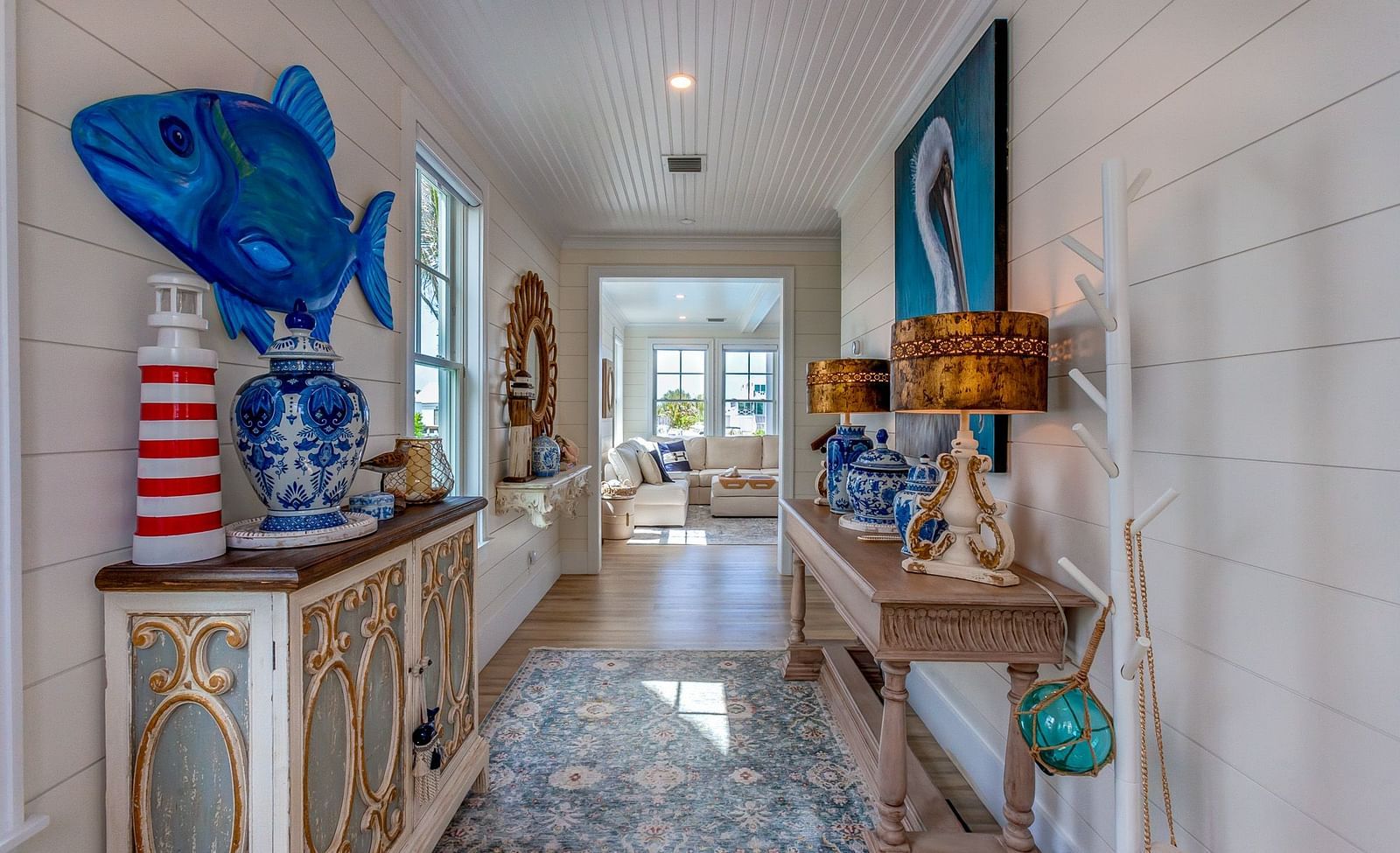 a corridor with colourful tiled floor and tables on the side with different decorative pieces, lamps, vases and wall arts at Abaco Inn.