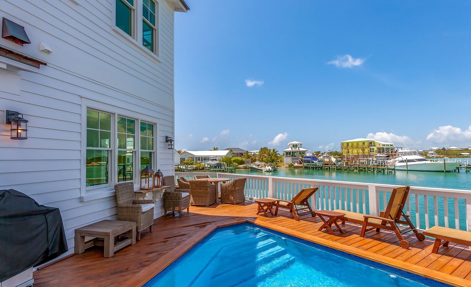 a swimming pool on a wooden dock and chairs with a sea view at Abaco Inn.