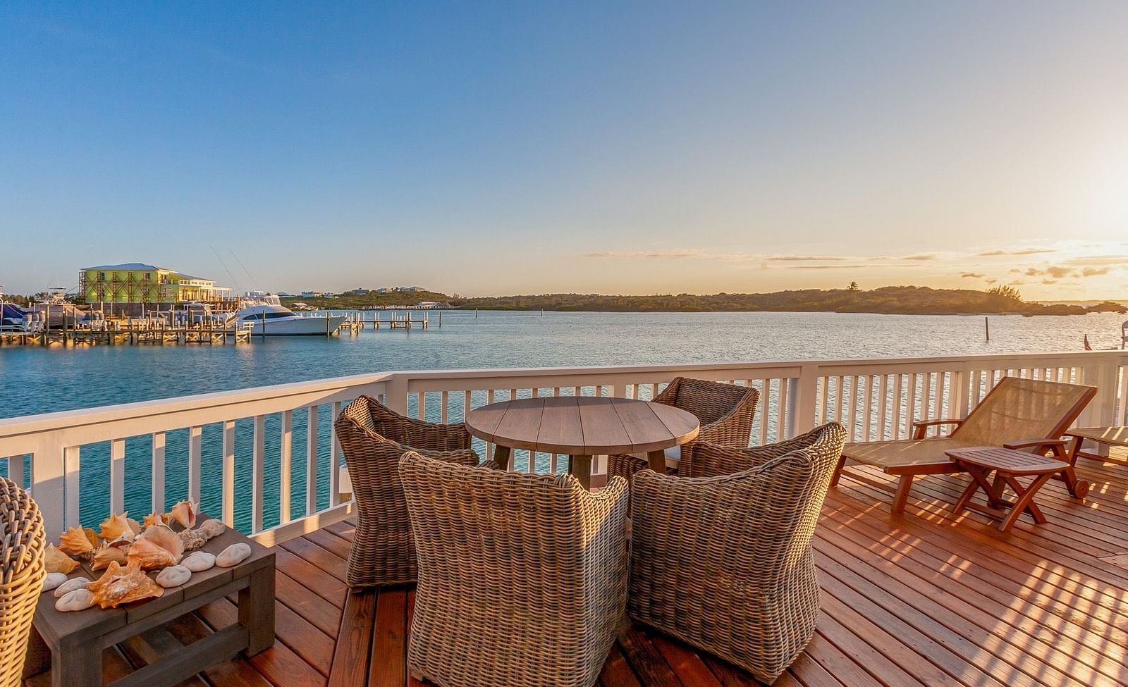 outdoor sitting area with wooden floor, tables and chairs and a view of the sea at Abaco Inn.