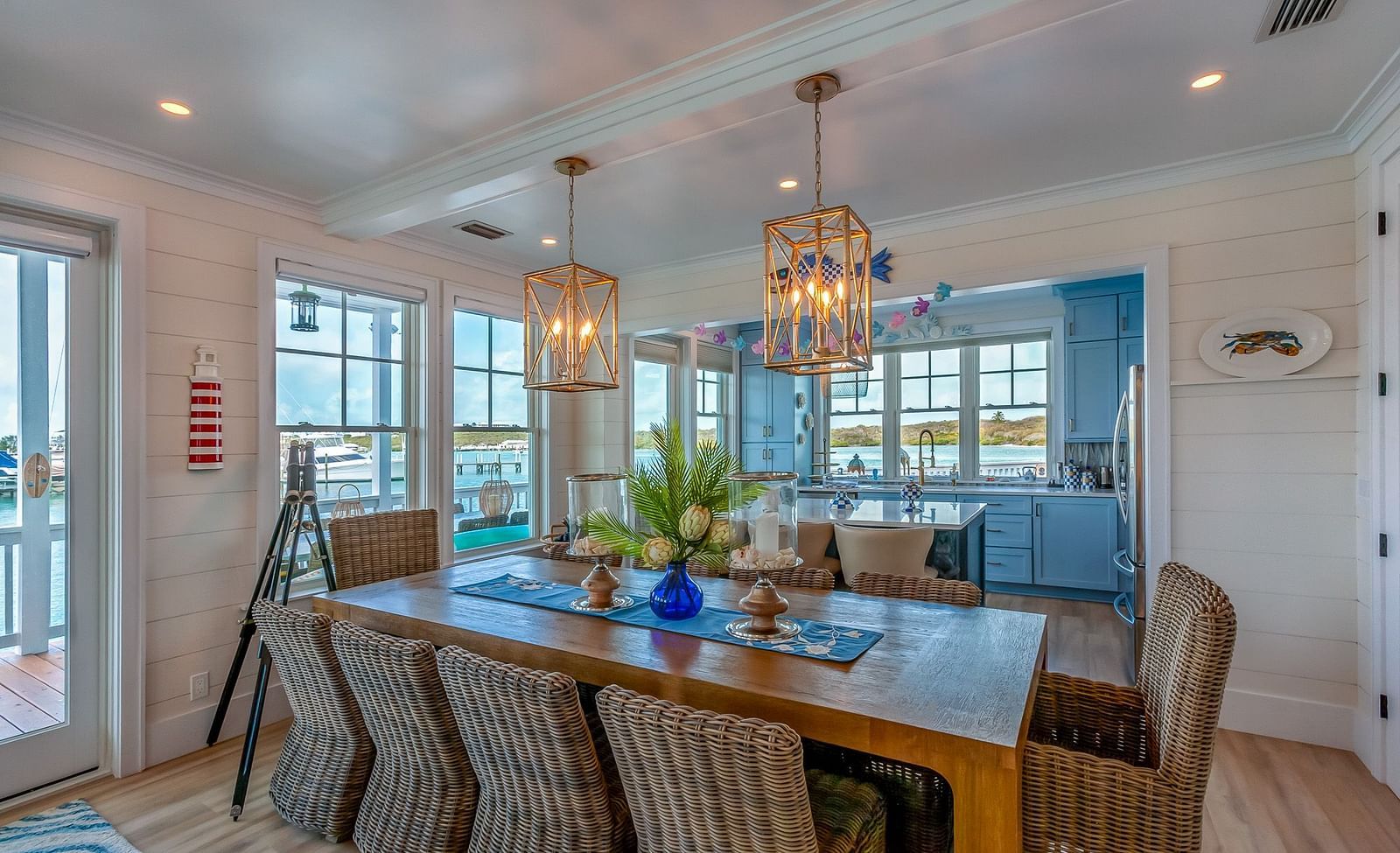 well lit kitchen with a dining area featuring wooden table and chairs, and windows overlooking the sea at Abaco  Inn.