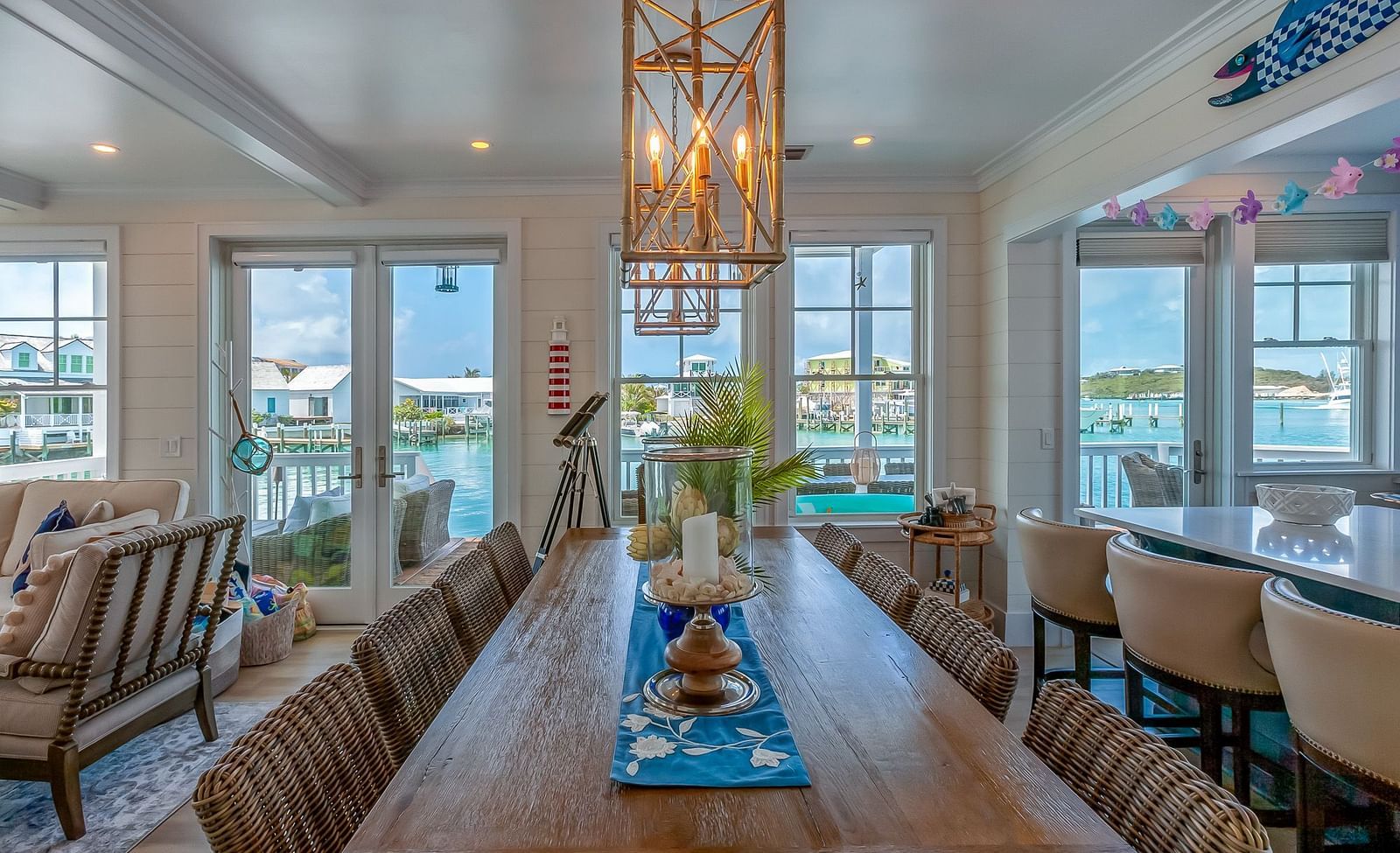 a wooden table with multiple chairs surrounding it and windows that overlook the sea.