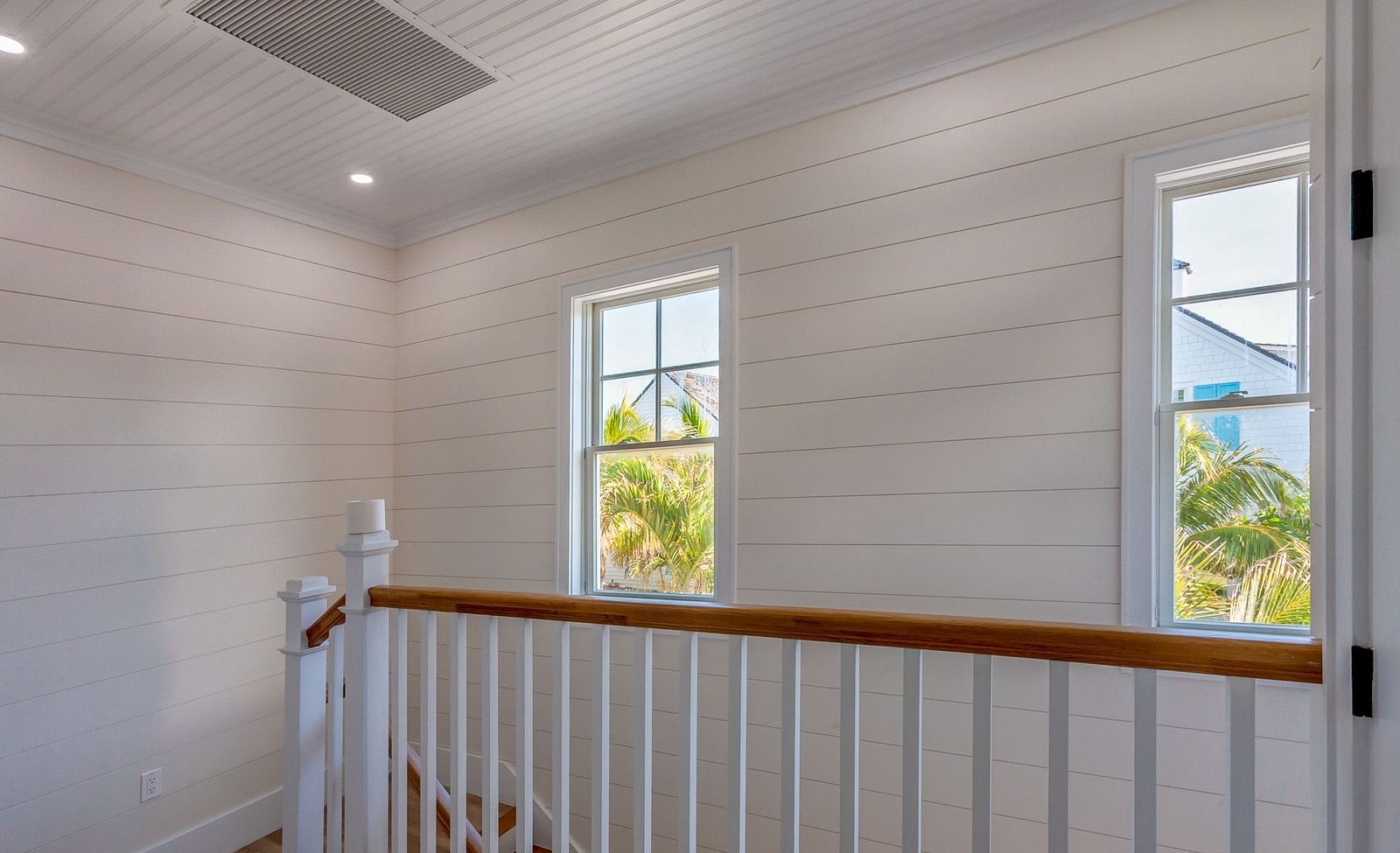 Stairways of Abaco Inn with white walls and windows overlooking greenery.