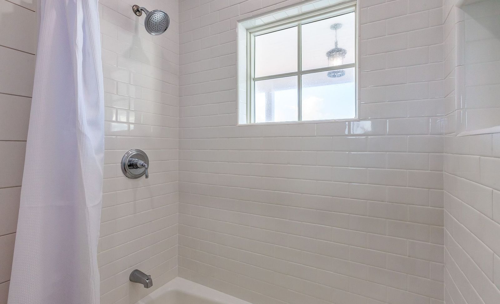 a bathroom of Abaco inn with curtained bathtub and shower, and a small window above.