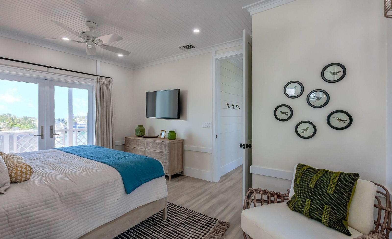 Spacious well lit bedroom with a comfortable bed, cupboards, a TV, sofa, wall decors, and a sliding door leading to the balcony with a sea view at Abaco Inn .