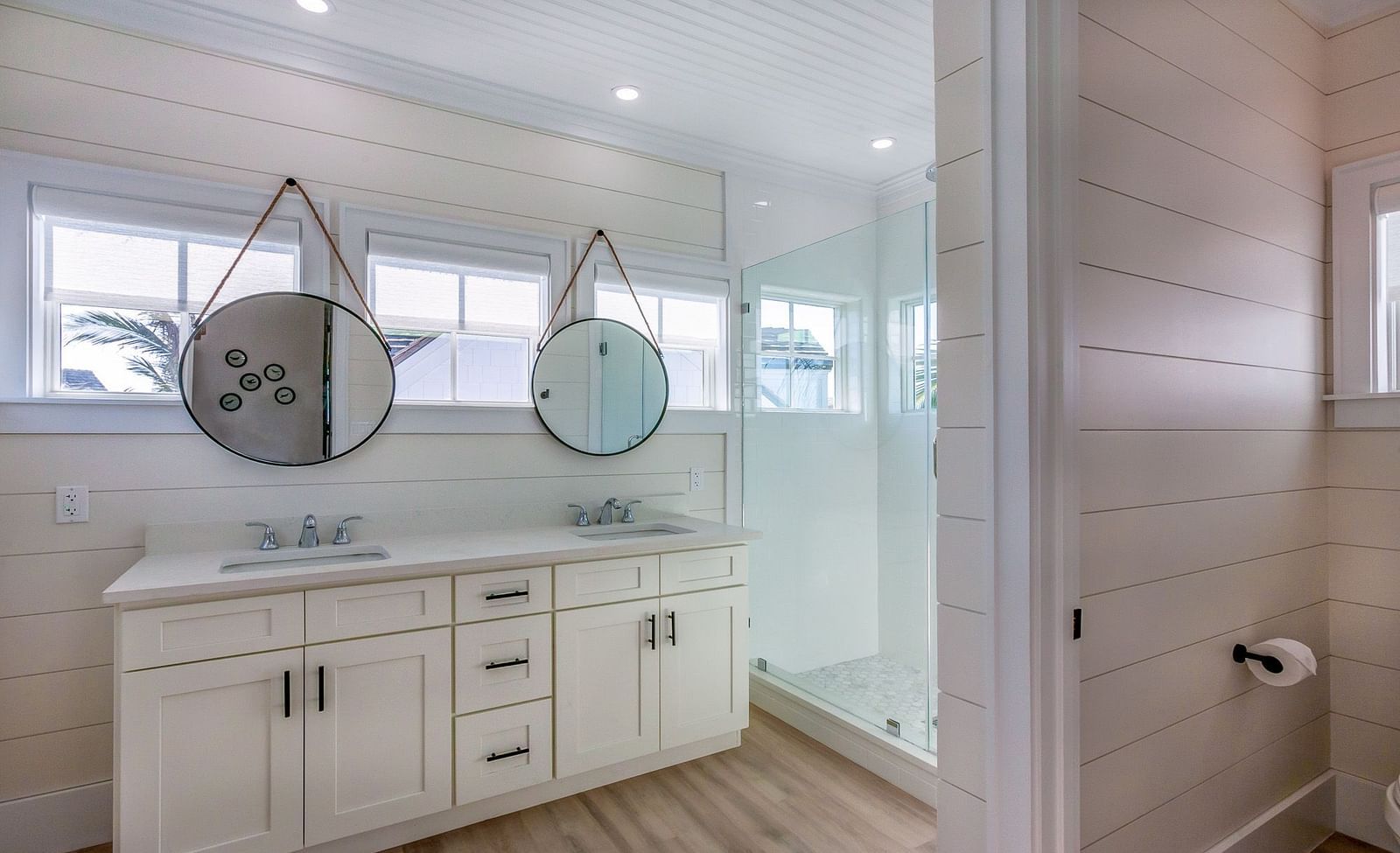 bathroom with cupboards, two sinks and two circular hanging mirrors at Abaco Inn.