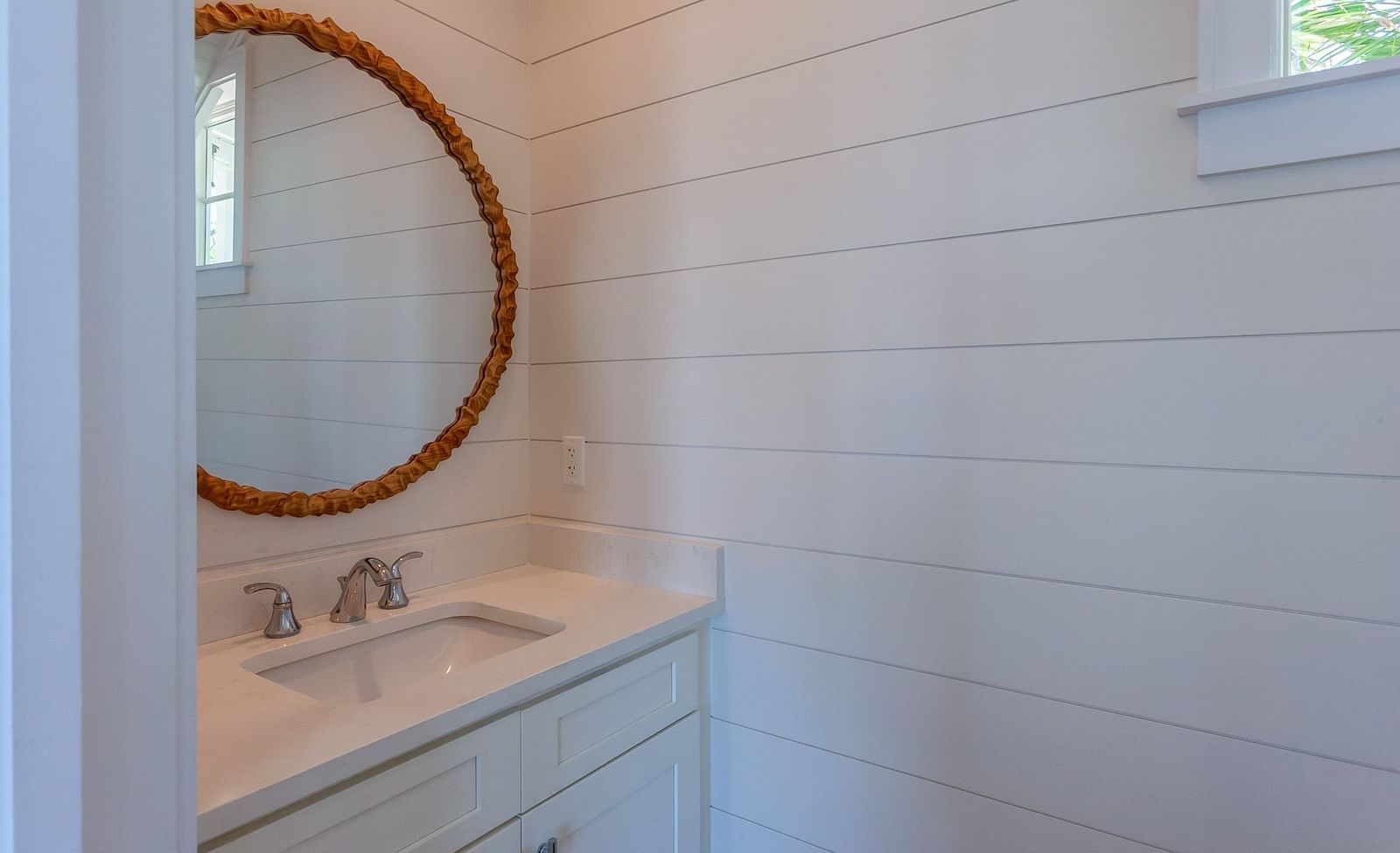 Bathroom with a sink , cupboard and a circular mirror at Abaco Inn.