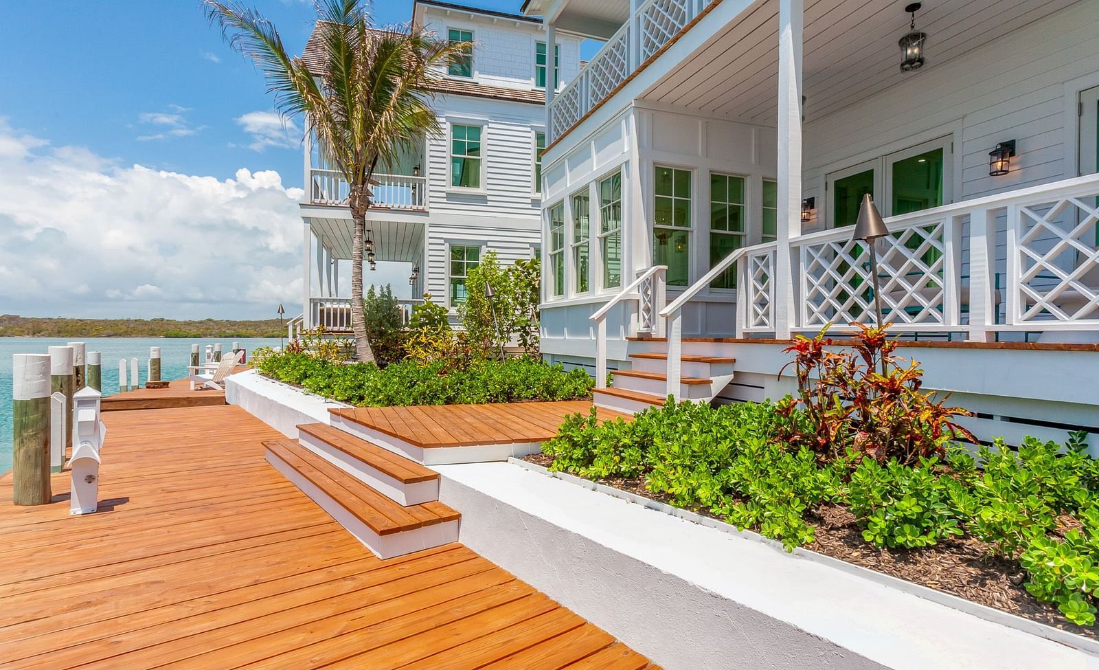 Facade of Abaco Inn with wooden dock, potted plants and a palm tree.