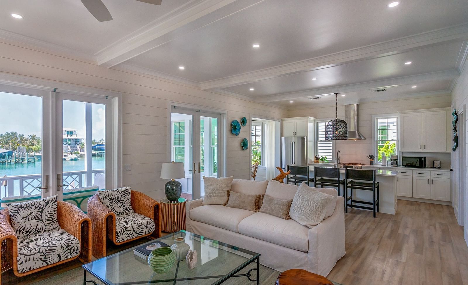 a sitting area with sofas, a glass table, chairs, wall decors and windows overlooking greenery at Abaco Inn.