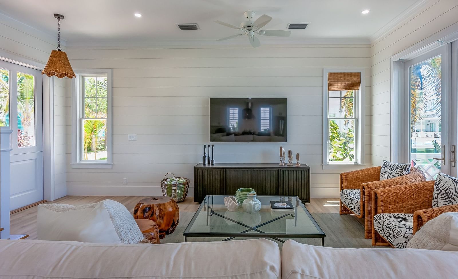 Sitting area of Abaco Inn with sofas, Glass table, TV unit, and windows overlooking greenery.
