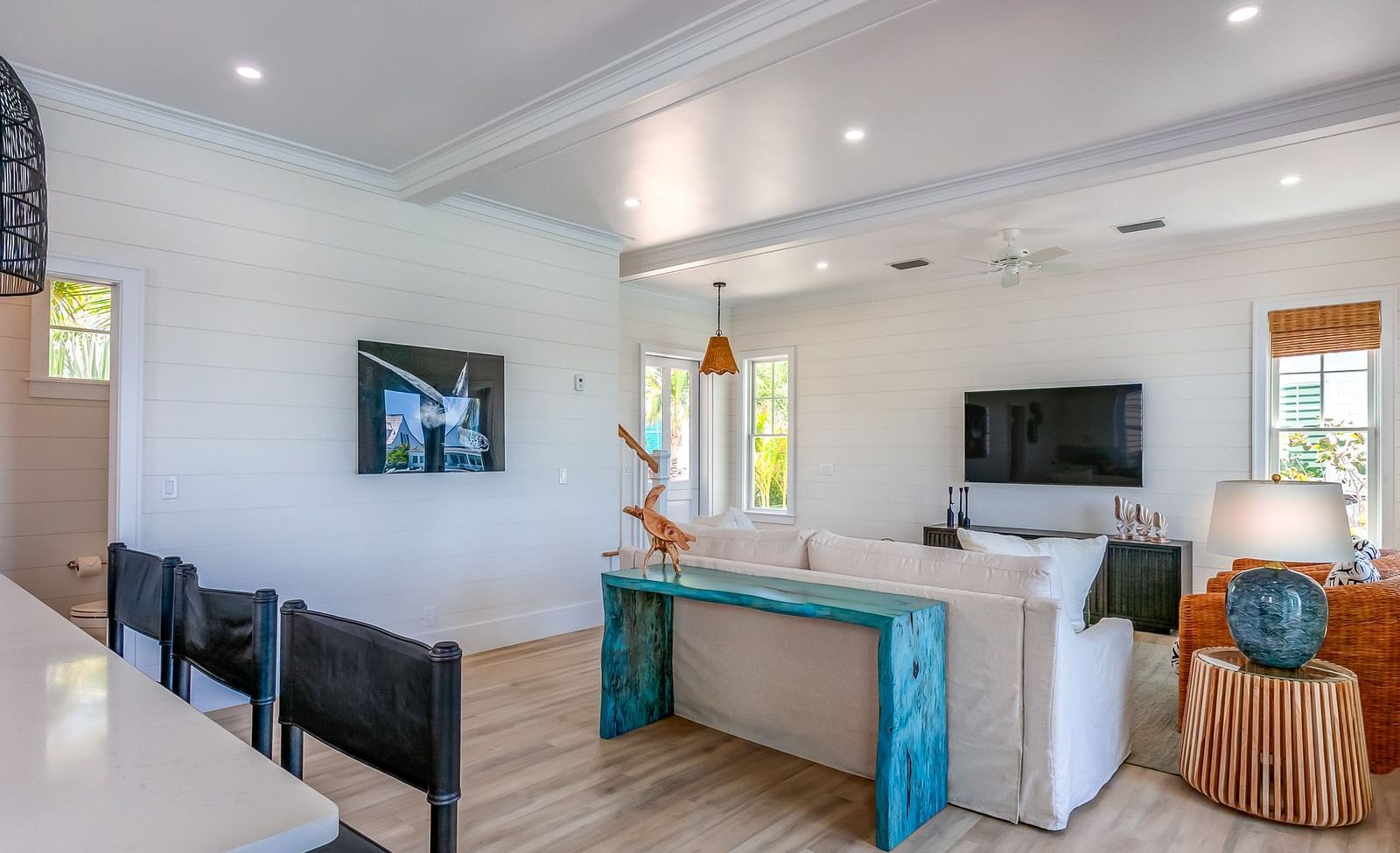 a sitting area with a sofa, TV, table, chairs, wall decors and windows overlooking greenery at Abaco Inn.