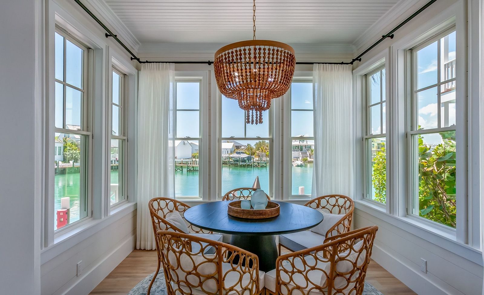 sitting area of Abaco Inn with a table and wooden chairs surrounding it, and windows overlooking the sea.