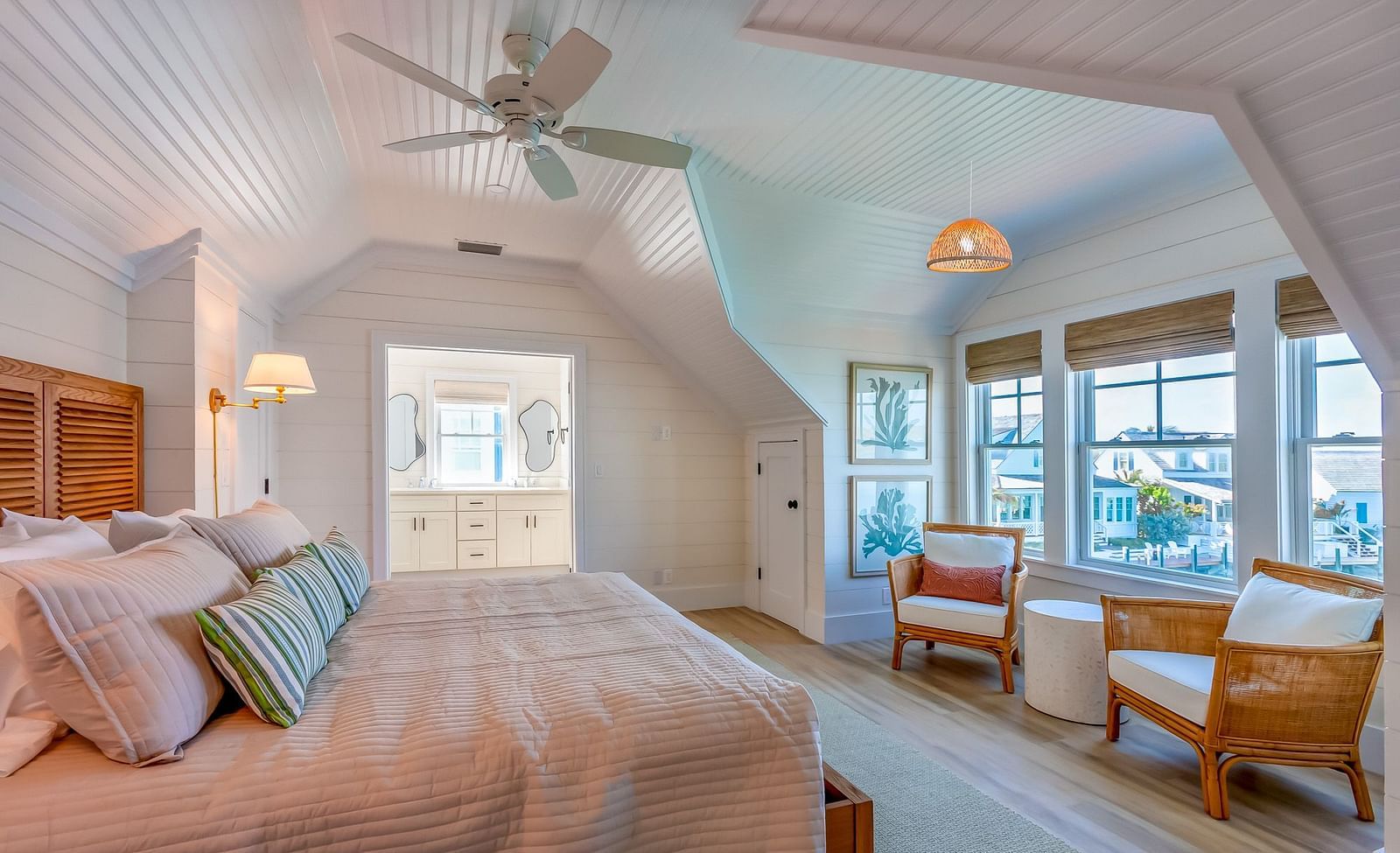 a bedroom at Abaco Inn with a huge bed, wooden floor, chairs, table, ceiling fan and windows overlooking the sea view.
