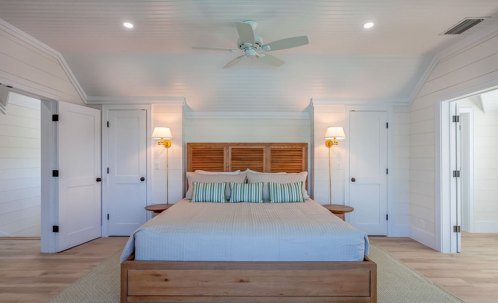 A spacious bedroom with a huge bed, ceiling fan, lamps and wooden doors at Abaco Inn.