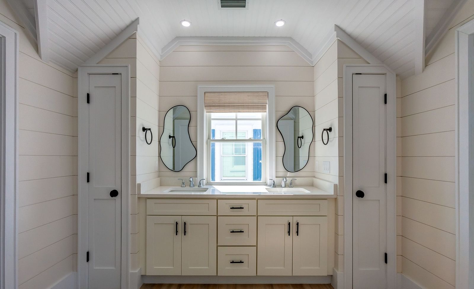 a bathroom with a sink, cupboards , mirrors and a window at Abaco Inn.