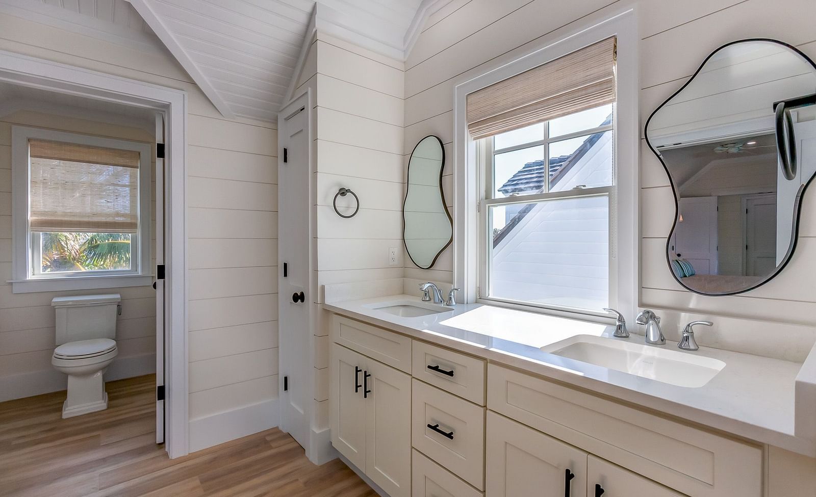 A bathroom with a commode, cupboards, sink, mirrors and a window at Abaco Inn .