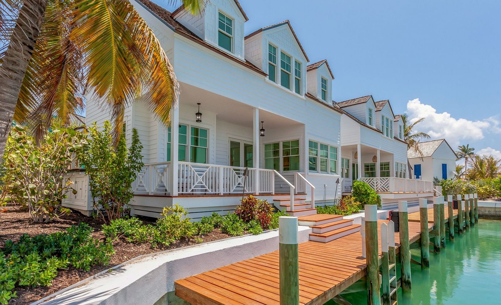 Facade of Abaco Inn with wooden dock, potted plants and a palm tree.