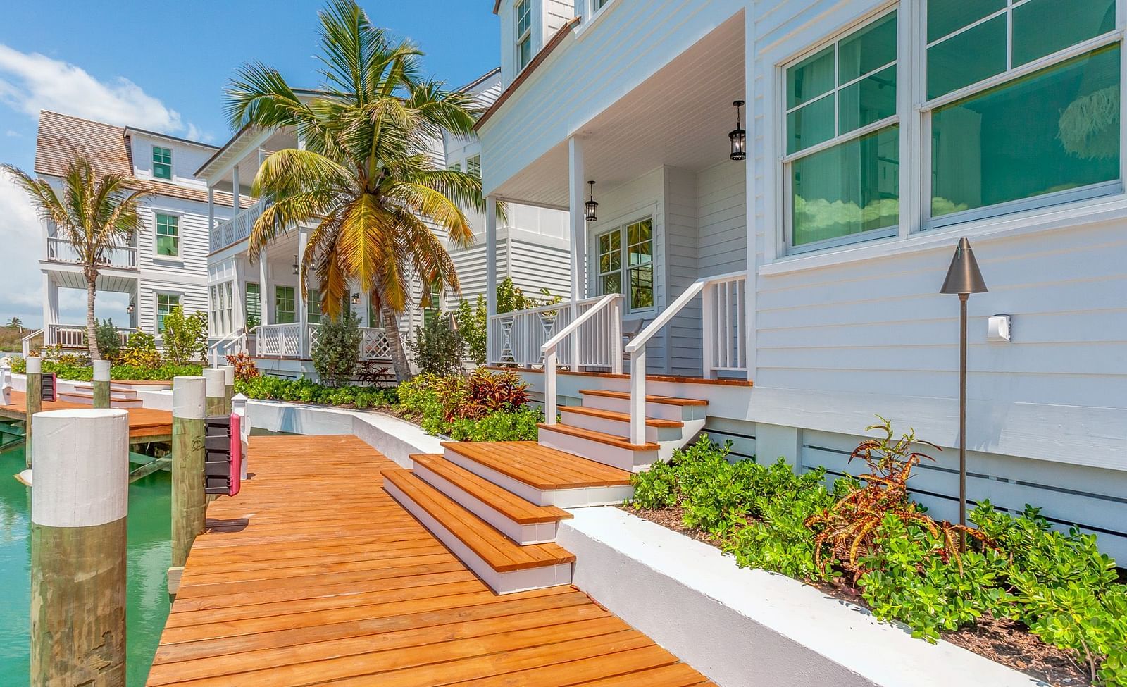 Facade of Abaco Inn with wooden dock, potted plants and a palm tree.