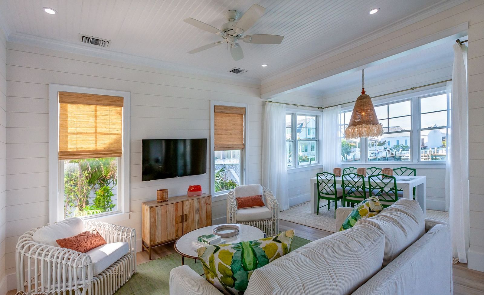 Sitting area at Abaco Inn with sofas, Table, Chairs, TV and windows overlooking  greenery.