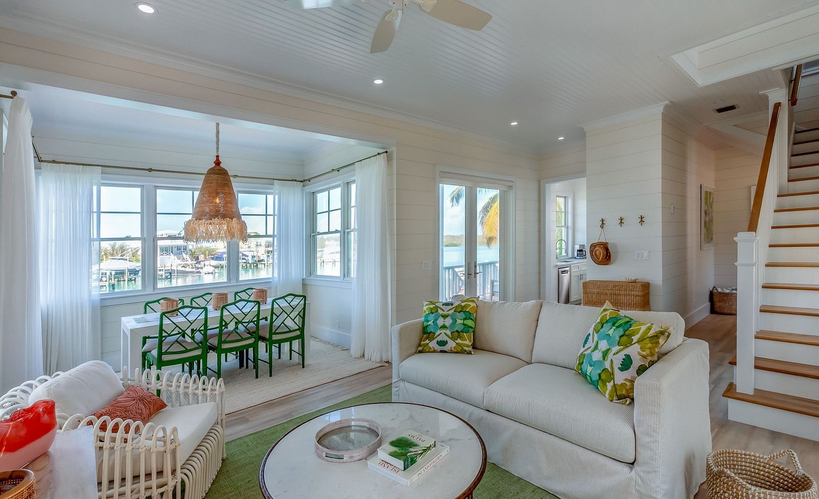 Sitting area at Abaco Inn with sofas, Table, Chairs, and windows overlooking  greenery.