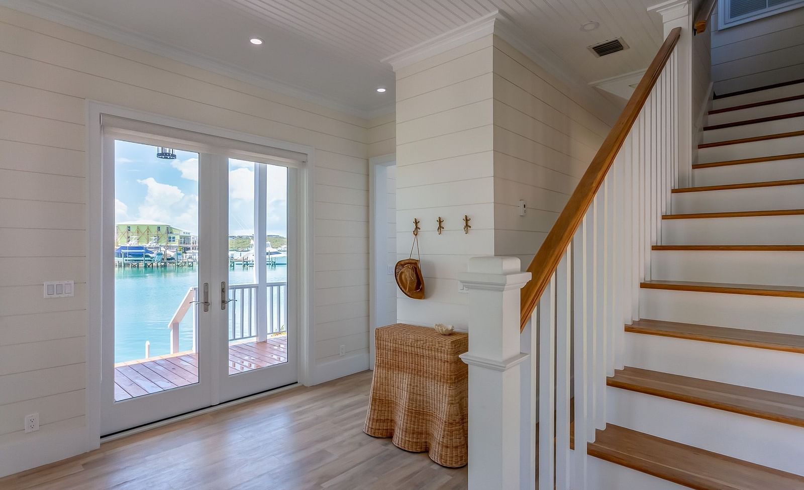 Stairways of Abaco Inn with wooden floor and sliding glass door leading to a dock with sea view.