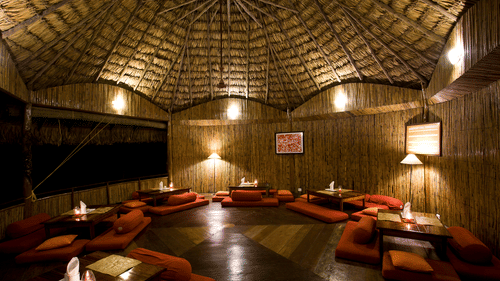 Wamly lit The Common Elephant featuring tables and plush seaters on the floor at Barefoot at Havelock, one of the beach resorts in Havelock, Andaman