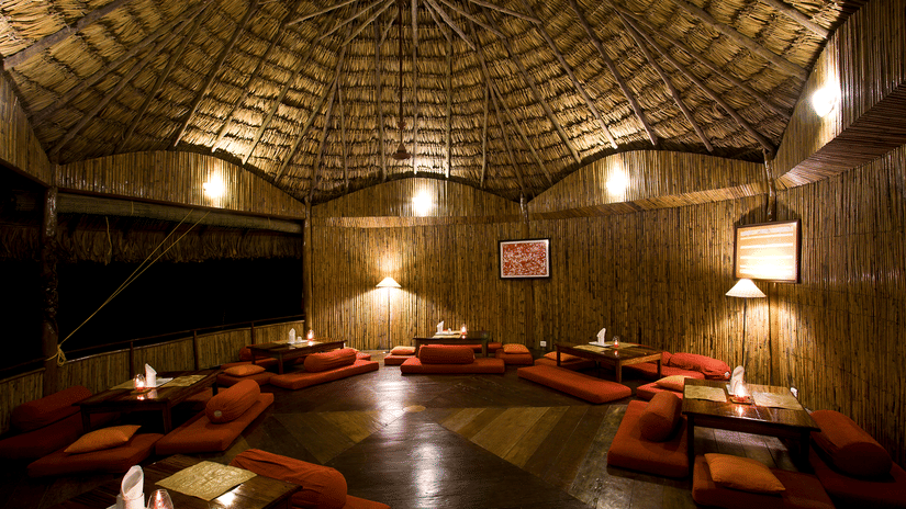 Wamly lit The Common Elephant featuring tables and plush seaters on the floor at Barefoot at Havelock, one of the beach resorts in Havelock, Andaman