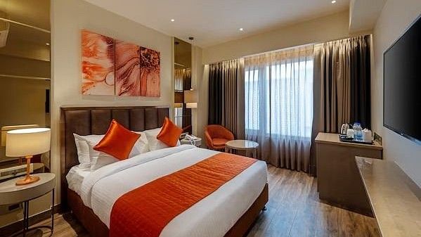 An image of a bedroom featuring a double size bed, a bedside table, a desk, a flat TV screen and much more - HOtel Saket 27