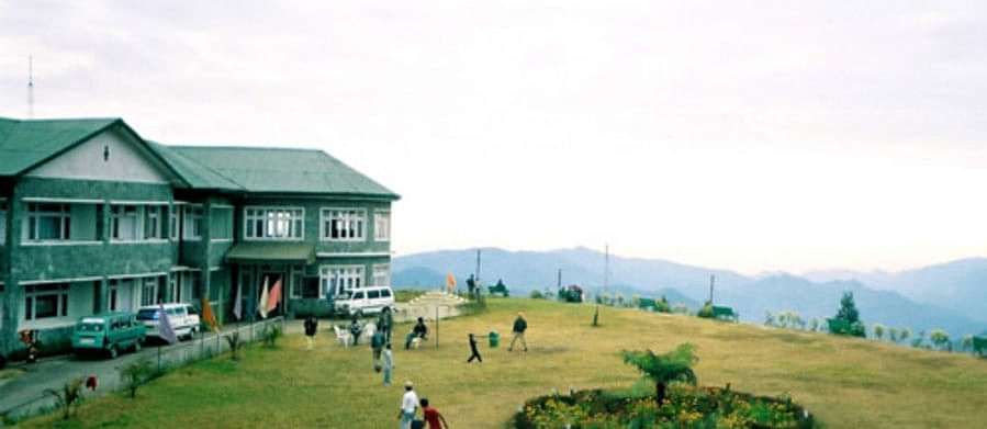 A building with a large lawn with mountains in the backdrop