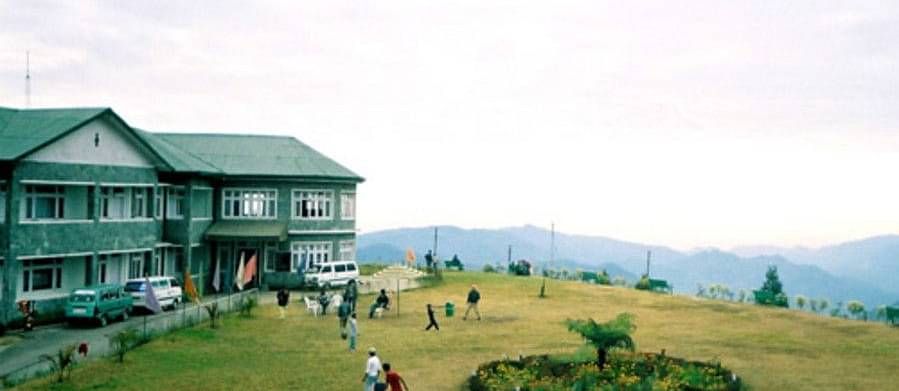 A building with a large lawn with mountains in the backdrop