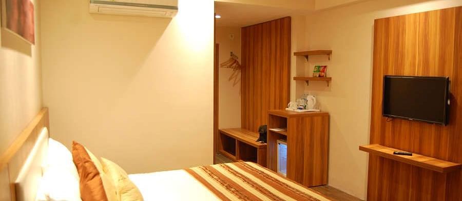 Corporate room with a posh bed and warm lighting captured from different angles while showcasing the in-5room amenities - the Le Roi Raipur Hotel