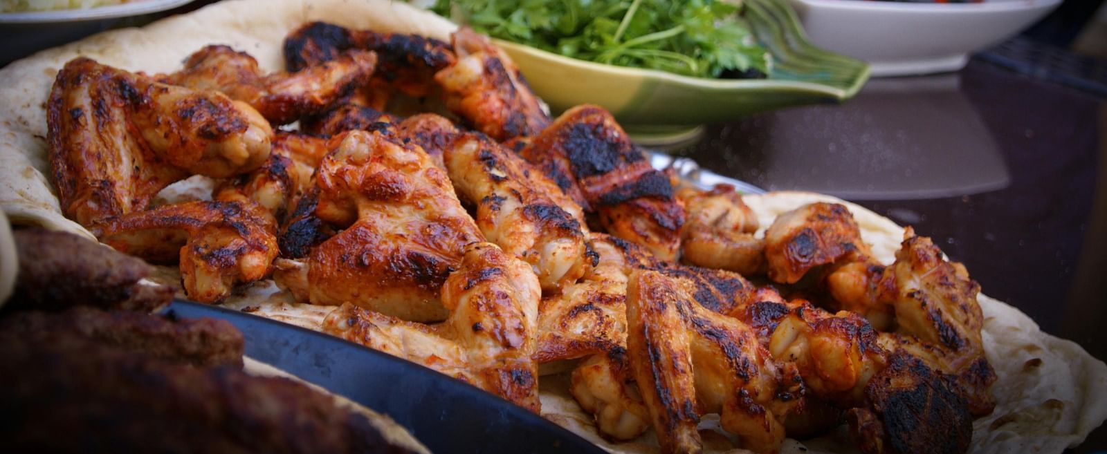 Close-up of grilled chicken skewers served with fresh green salad and vegetables.