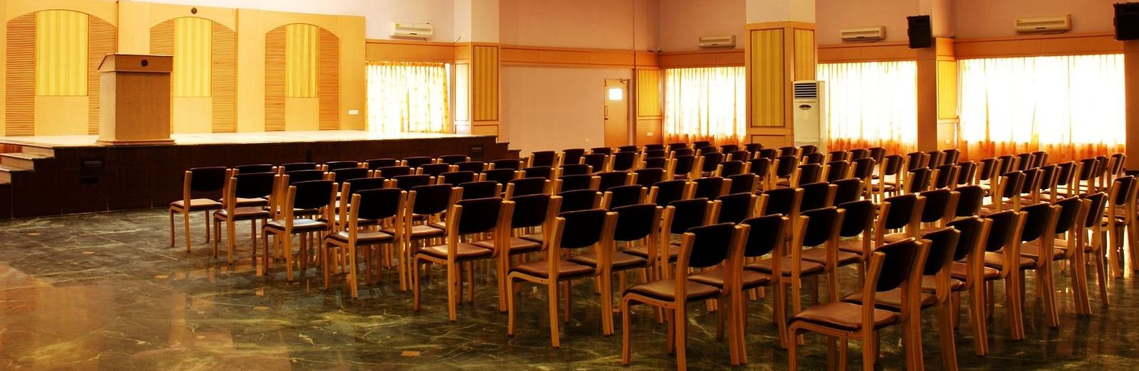 A view of a banquet hall at Paradise Isle Beach Resort, Udupi with a chandelier and a theatre style seating arrangement