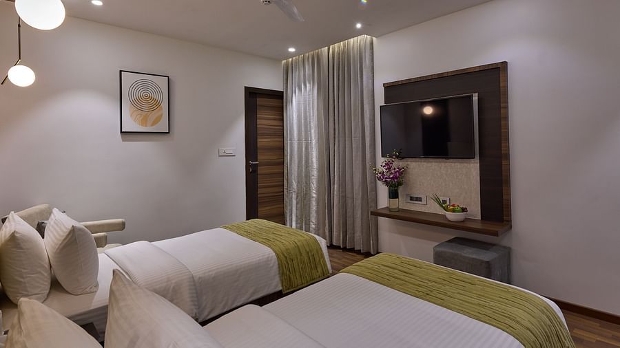 Side view of the twin beds and tv wall mounted in executive room at Grand Continent - A Sarovar Premiere Affiliate Hotel, Hosur