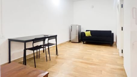 Open-plan living room with sofa, table, and wooden floor at The Pinnacle, Electronic City.
