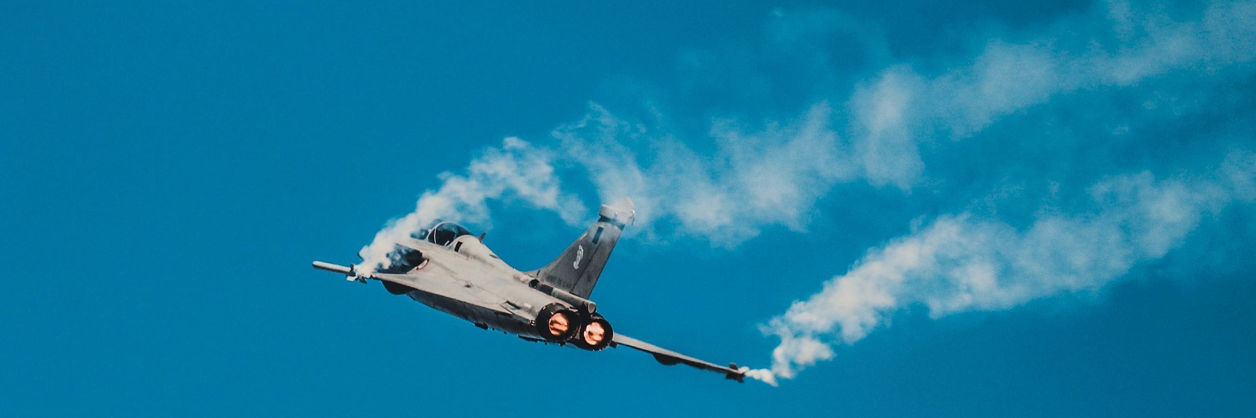 A jey flying in the air with smoke coming out of the wings