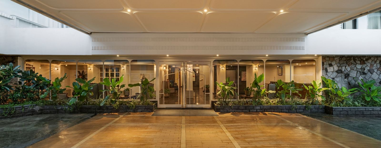A brightly lit entrance of a hotel featuring tiled floors and potted plants - Shilton Hotels
