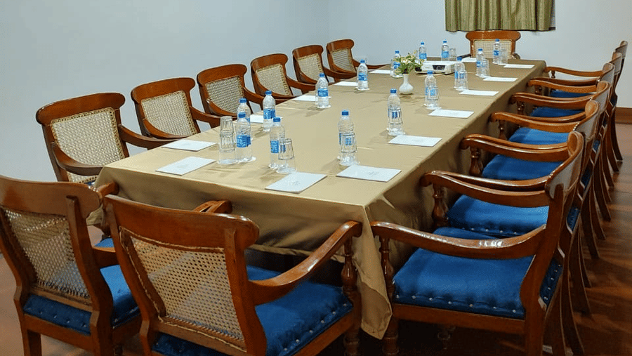 Boardroom with a long wooden table, blue-cushioned chairs, and a traditional wooden ceiling, offering one of the ideal meeting rooms in Trivandrum at The Travancore Heritage Beach Resort.
