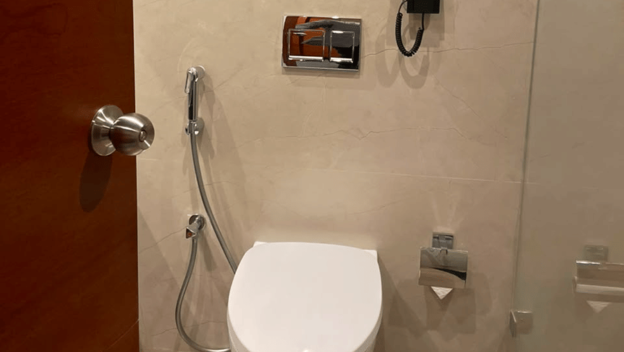 MM Legacy, Kanchipuram | A bathroom with a toilet seat, towels, and other toileteries.