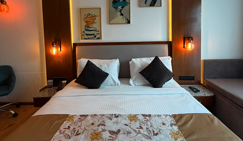 Deluxe Room with a king bed dressed in a floral runner beneath cove lighting and framed portrait art
