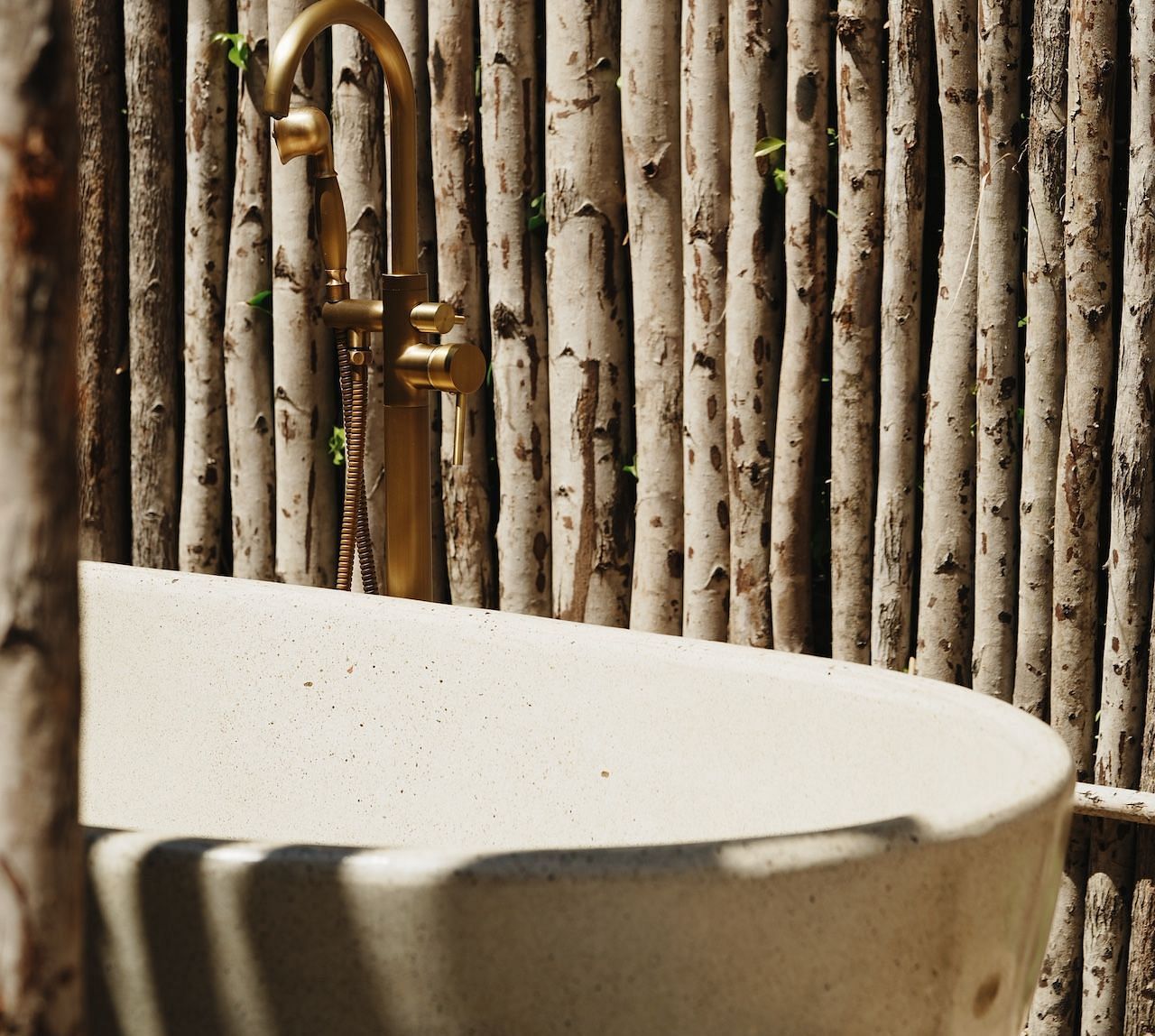 An outdoor bath area at the Peaceful Tent in WoCAL Retreat Ke Ga, featuring a freestanding tub surrounded by a natural bamboo screen, evoking the essence of rustic luxury in nature.