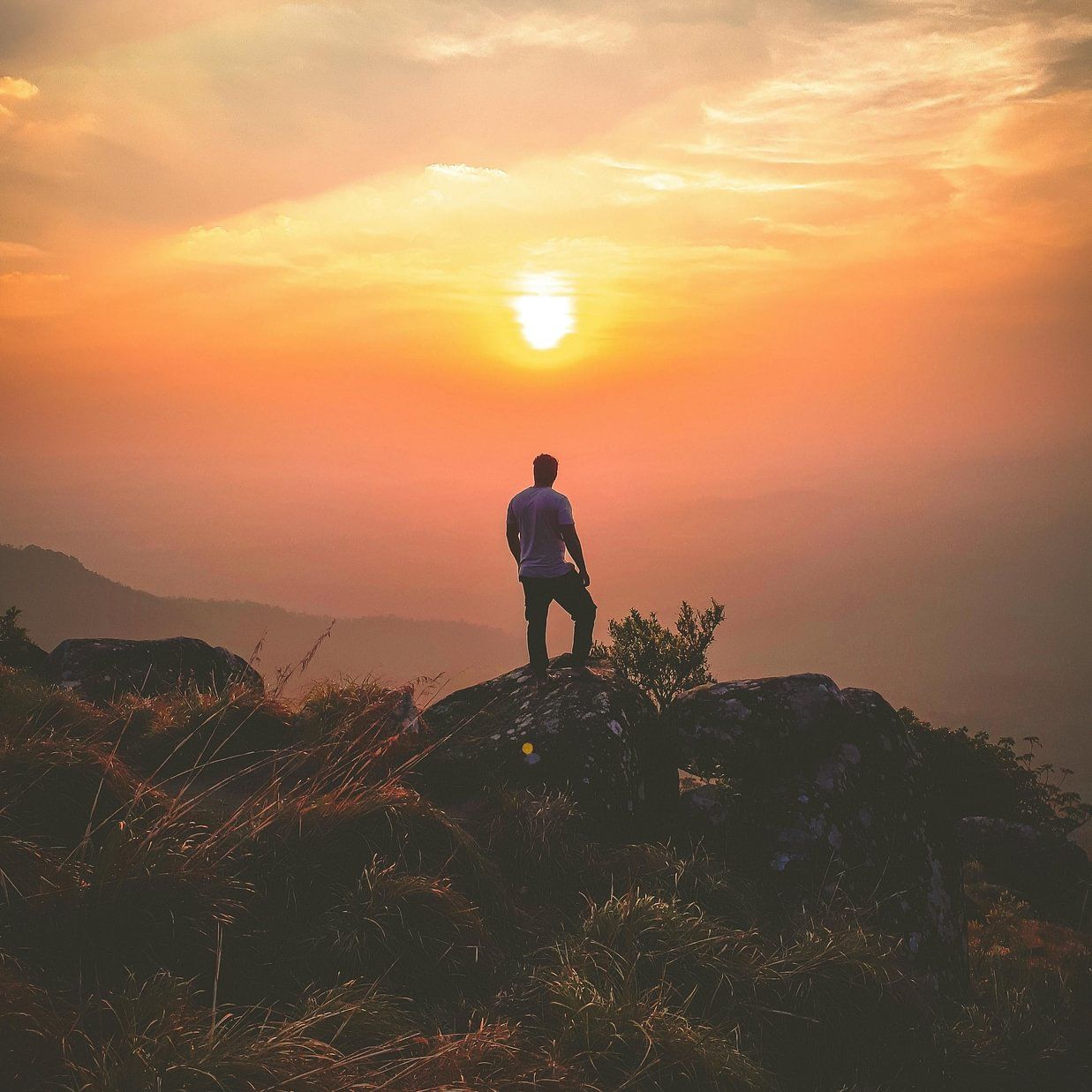 Man watching orange sunset mountain top