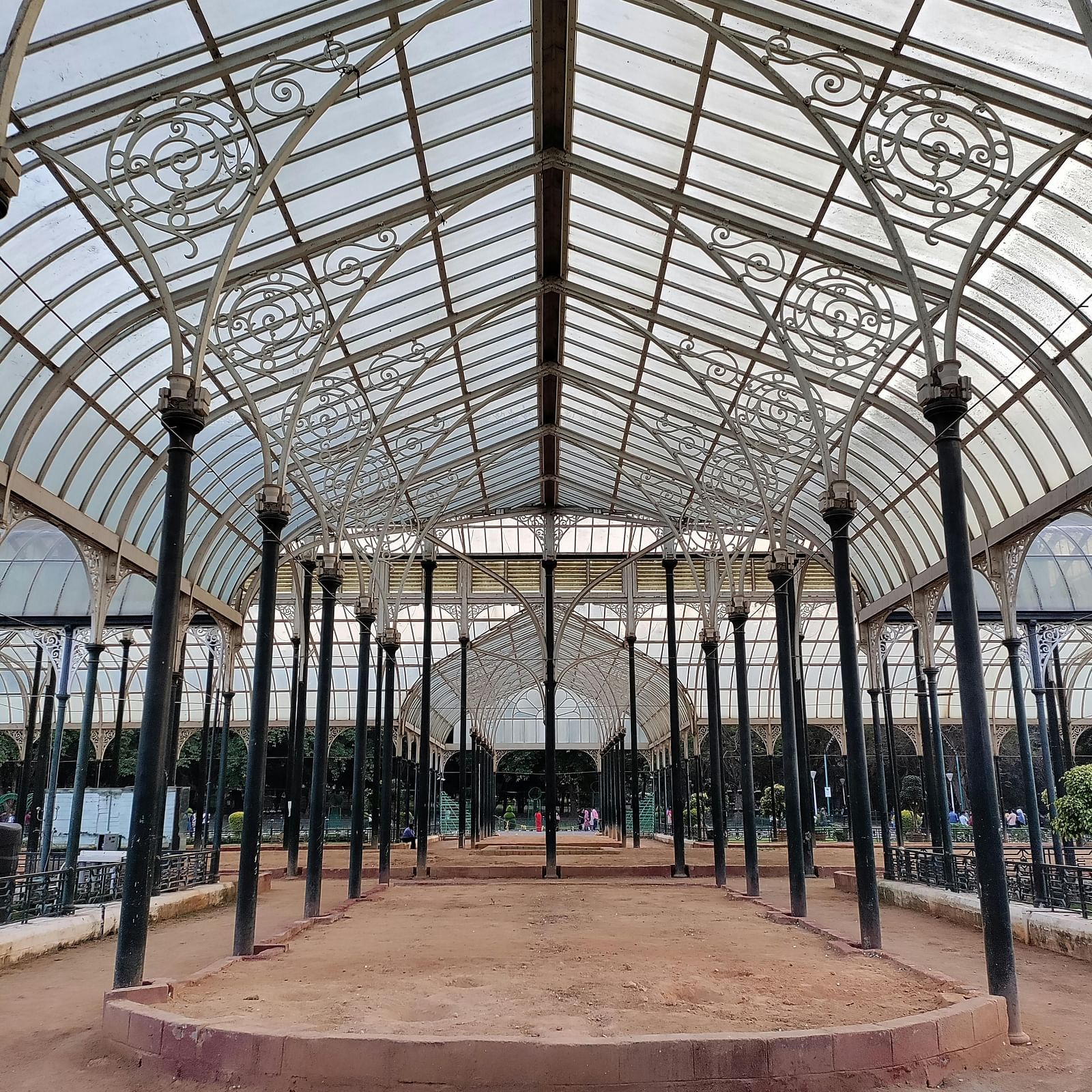 a garden covered with translucent sheds supported by tall black coloured pillars 