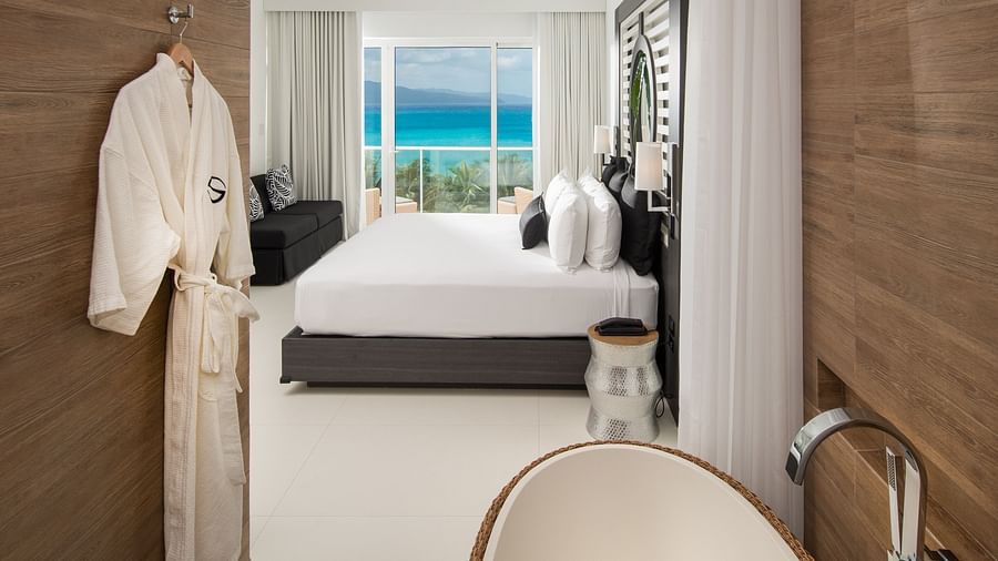 A view of a suite from the bathroom encompassing a bed, a couch and a balcony with views - S Hotel Montego Bay, Jamaica