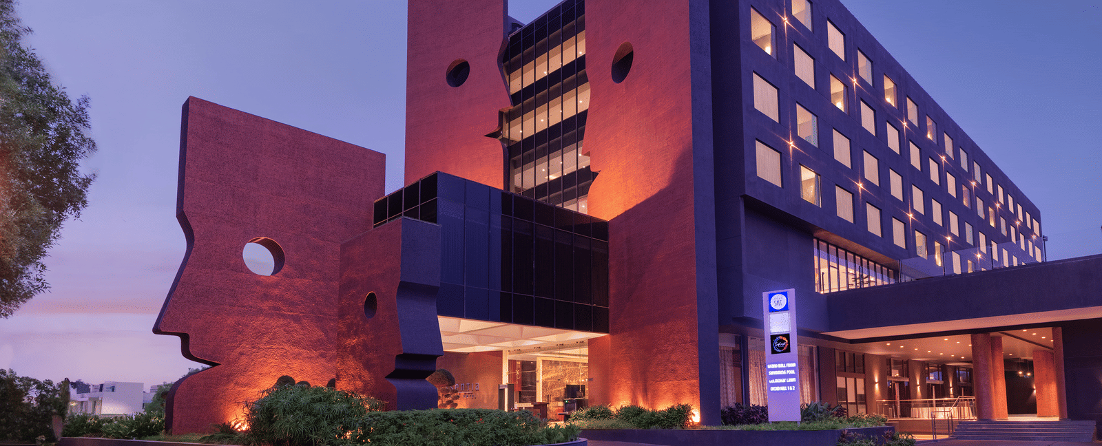Far out facade view of Essentia Luxury Hotel, Indore during blue hour with the lights on.
