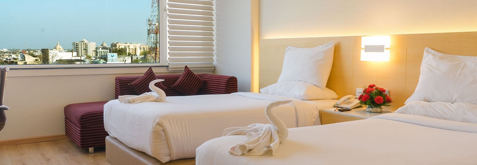A side view of twin beds in a room with a huge glass window | Gemini Continental
