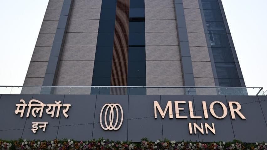 A tall building with a sign reading 'Melior Inn' at its base is shown against a partly cloudy sky.