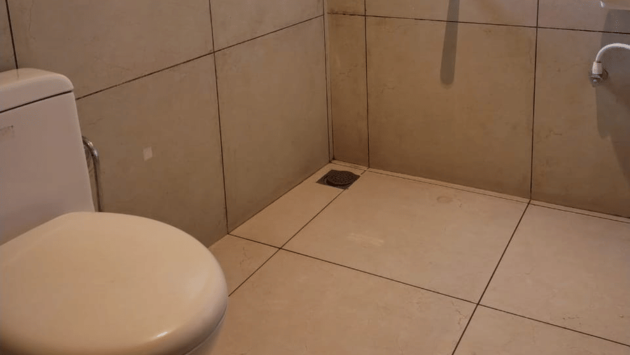 Bathroom of Lawn View Room at Cholaa Dynasty, Kumbakonam featuring a commode, faucet, sink, and other bathroom facilities.