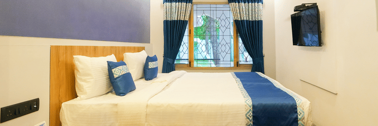 An image of a room with a bed, bed side table, and a window overlooking the view - MGM Whispering Nest