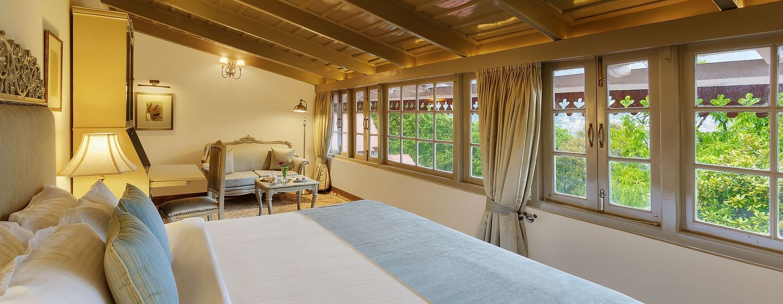 A lush room with cosy decors, king size bed with pillows and soft cushions, wooden ceiling overseeing the mountain views- The Naini Retreat